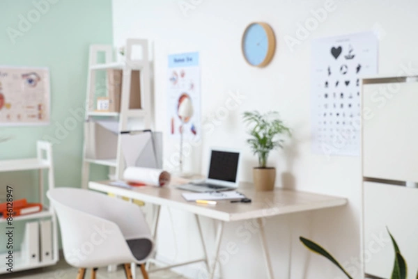 Fototapeta Blurred view of ophthalmologist's office with workplace and eye test chart