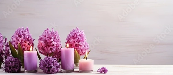 Fototapeta A copy space image of hyacinth flowers and candles arranged on a wooden table placed near a white wall
