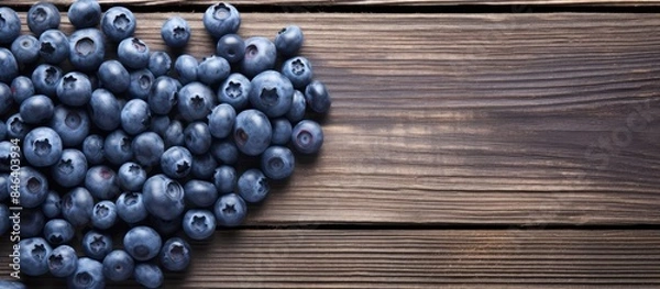 Fototapeta A heart shaped arrangement of blueberries on a wooden surface creating a visually appealing copy space image