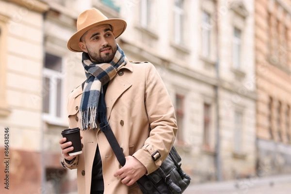 Fototapeta Handsome man in warm scarf with paper cup outdoors. Space for text