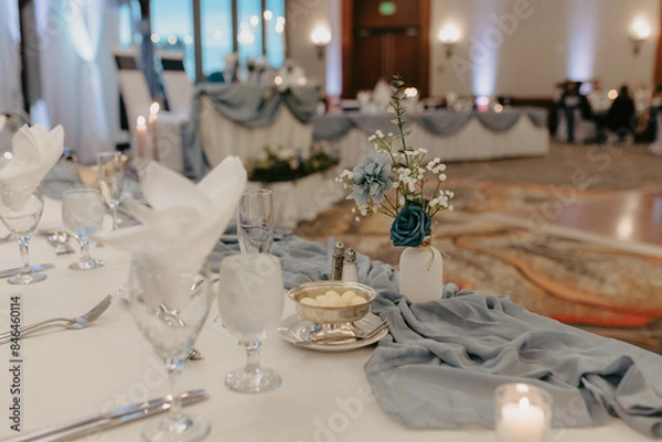 Fototapeta Table adorned with blue fabric, candles, and floral centerpieces