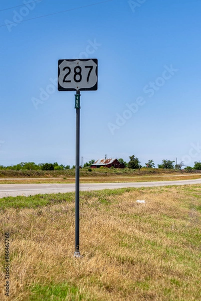 Obraz a street sign by a road that has a large number plate on it