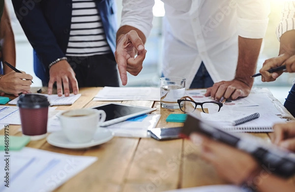 Fototapeta Business people, hands and pointing with tablet and documents in meeting for collaboration on project at office. Group of employees, conversation or discussion with paperwork for brainstorming