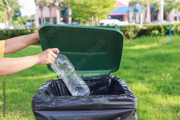 Fototapeta Hand throwing empty plastic bottle into the trash