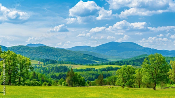 Obraz picturesque landscape of green hills and blue mountains under bright sky with fluffy clouds