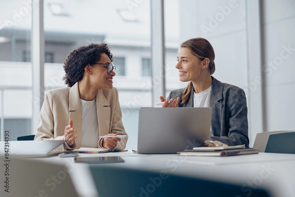 Fototapeta Coworkers discussing biz related problem in the office and using laptop. Conception of business team