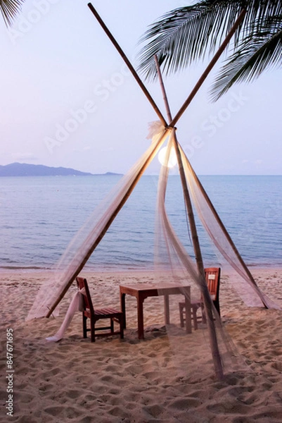 Fototapeta Romantic beach dining under a tent with an ocean view, ideal for a sunset meal by the sea