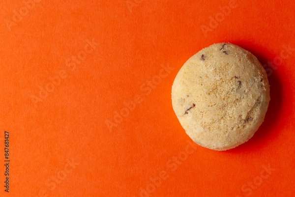 Fototapeta On an orange background, A piece of coconut butter bakery cookie. Top-down view. Food Flat lay.