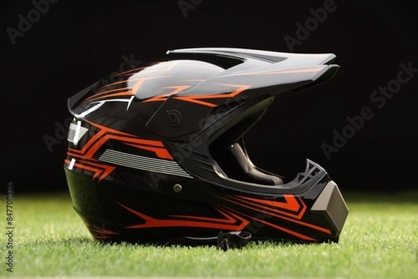 Obraz Modern motorcycle helmet with visor on green grass against black background