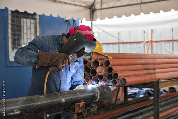 Obraz Worker welding the steel part by manual