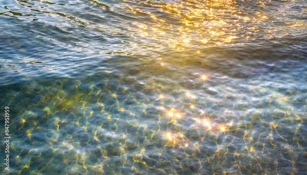 Fototapeta water waves of the sea and ocean with glare and rays of the sun, summer wallpaper for the presentation of recreation and vacation