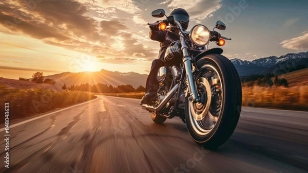 Fototapeta A motorcyclist rides on a scenic highway at sunset, capturing the spirit of adventure and freedom on the open road.