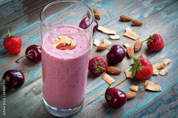Obraz Greek yogurt smoothie milkshake topped with goji berries and coconut shavings.A nutritious breakfast served on a rustic wooden tray