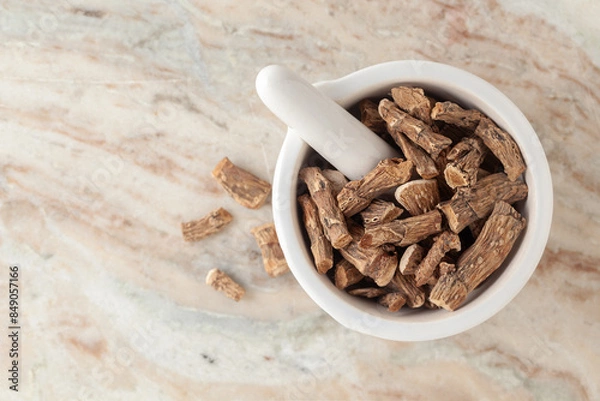 Obraz Top-view of Dry Organic Sweet flag or Vach (Acorus calamus) roots, in white ceramic mortar and pestle, on a marble background.