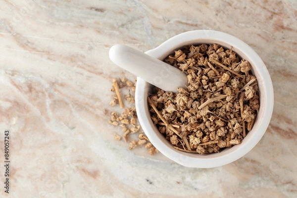 Obraz Top-view of Dry Organic Gokhuru (Tribulus terrestris) fruits, in white ceramic mortar and pestle, on a marble background.