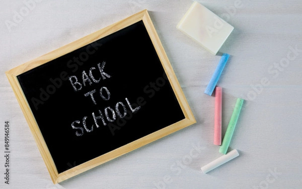 Fototapeta Black school blackboard with "Back to School" and chalk next to it. Top view. For backgrounds and presentations