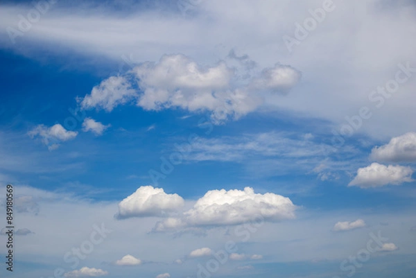 Fototapeta White cumulus clouds form against a vibrant blue sky