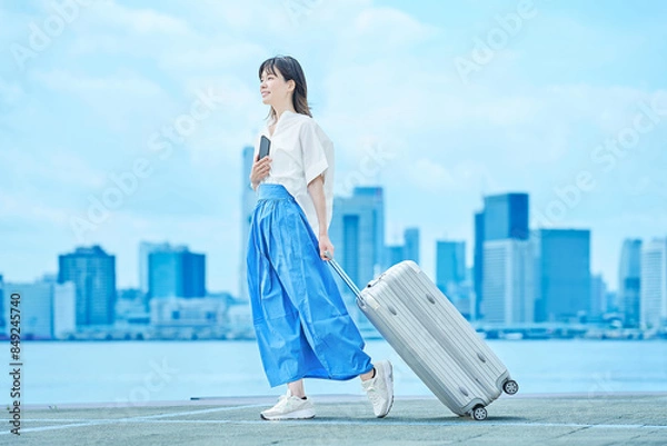 Fototapeta スーツケースを手に歩く若い女性