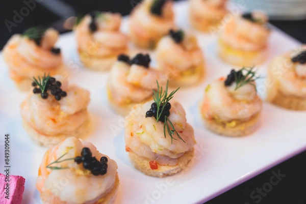 Fototapeta Beautifully decorated banquet catering table, with variety of with different food snacks appetizers on corporate birthday party event or wedding celebration, canape, salad, delicatessen setting