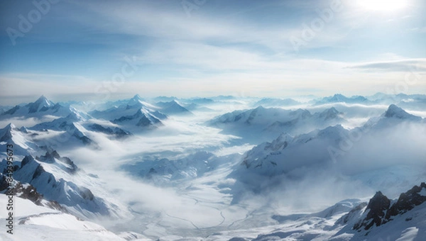 Fototapeta a mountain range covered in snow and clouds