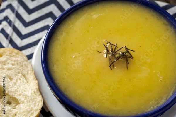 Fototapeta Delicious cassava cream (Caldo ou Creme de Mandioca) or cassava soup, typical of Brazilian cuisine, served in a blue porcelain bowl, on top of a typical rustic farm table, top view with selective focu