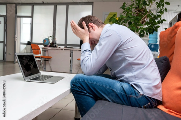 Obraz Young handsome man with computer in the office.