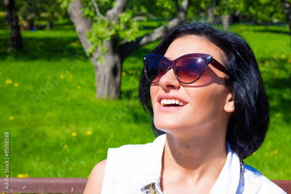 Fototapeta Attractive brunette in sunglasses laughing in the park on a sunny day