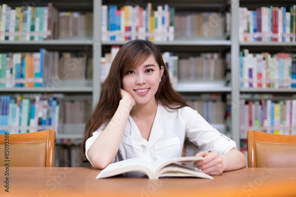 Obraz Beautiful asian female student read book in library with bookshe