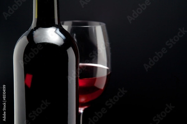 Obraz Red wine glass and a bottle in black background