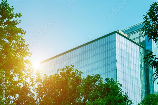 Fototapeta Environmentally friendly office building a sustainable glass building with trees reduces heat and carbon dioxide. Office buildings with a green environment save energy and allow employees to relax.