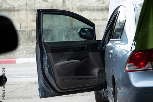 Obraz A car is parked on the side of the road with its door open