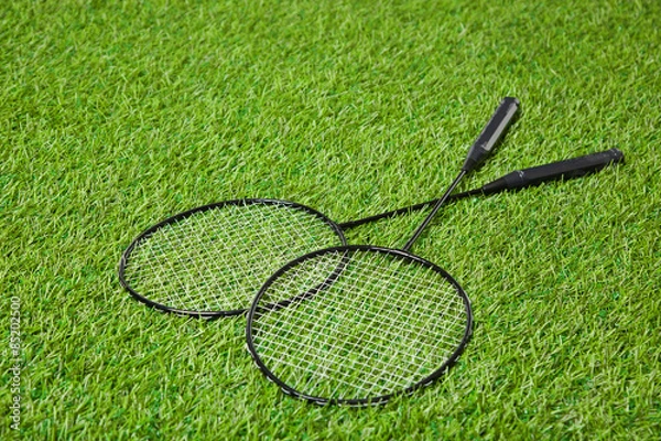 Fototapeta Crossed badminton rackets lying on grass