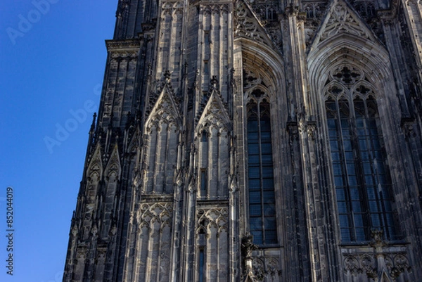 Fototapeta Gothic facade and windows of Hohe Domkirche St. Petrus (Cologne Cathedral) with blue sky in Cologne, Germany