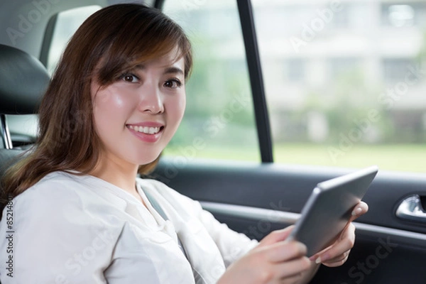 Fototapeta Beautiful asian woman using digital tablet in car