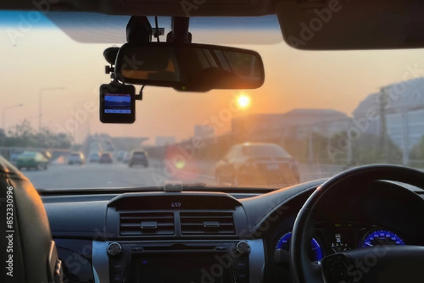 Fototapeta Bright and clear image interior of the car show steering wheel, dashboard, car stereo, car camera and air conditioning ventilation with traffic outside on summer morning background.