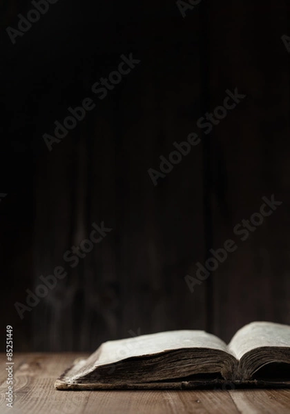 Fototapeta Image of a book on wooden background in a dark space