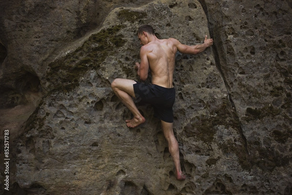 Fototapeta young man climbing on a rock, bouldering