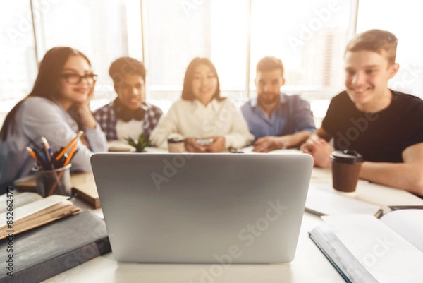 Fototapeta Diverse students studying for school assignment, using laptop in college library