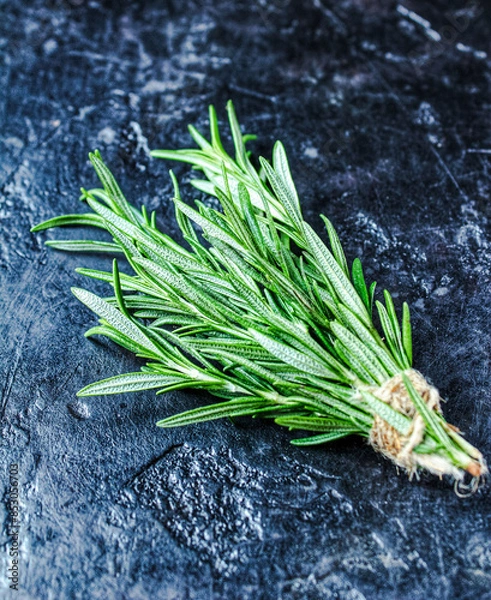 Fototapeta Rosemary on a black background. A bunch of fresh green fragrant rosemary. Spices and herbs that are used for cooking meat and fish. Culinary concept.