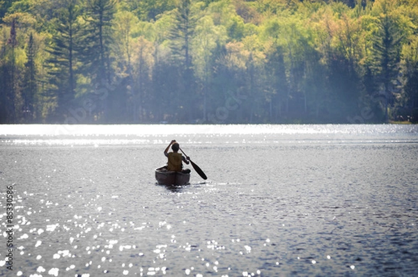 Obraz boy paddling a canoe across a lake