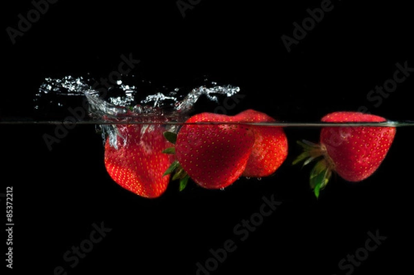 Obraz Strawberries splashing into water