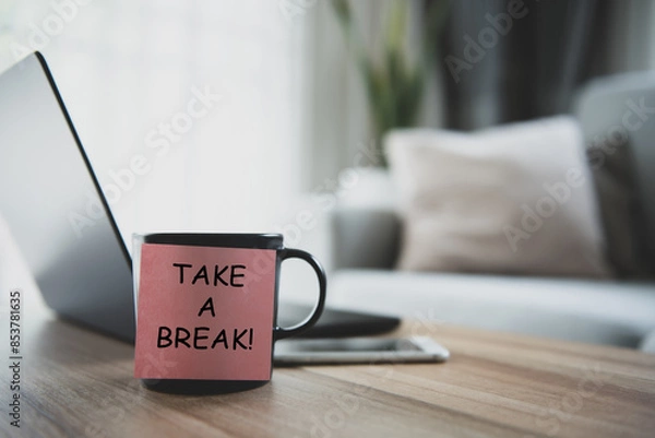 Fototapeta Take a break is written on a post-it and stuck on a coffee mug on my desk. It's a reminder that it's time to take a break from work.
