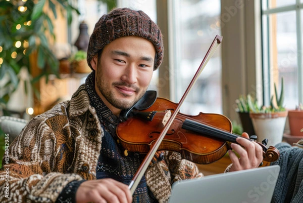 Fototapeta Virtual Virtuoso: College student masters violin through online lessons on laptop