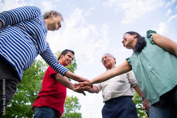 Obraz A  family of four is playing on a cloudy day, holding hands in a circle. 