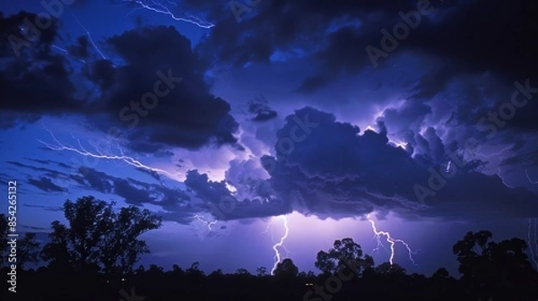 Fototapeta A thunderstorm illuminating the night sky a result of lightning creating photons in the air.