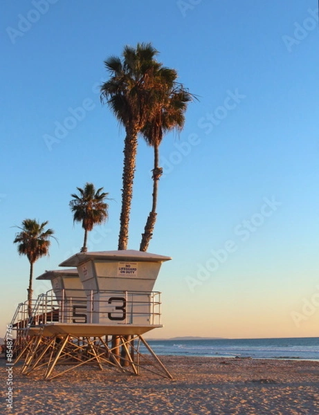 Obraz Life guard tower with palm trees as the sun sets in California 