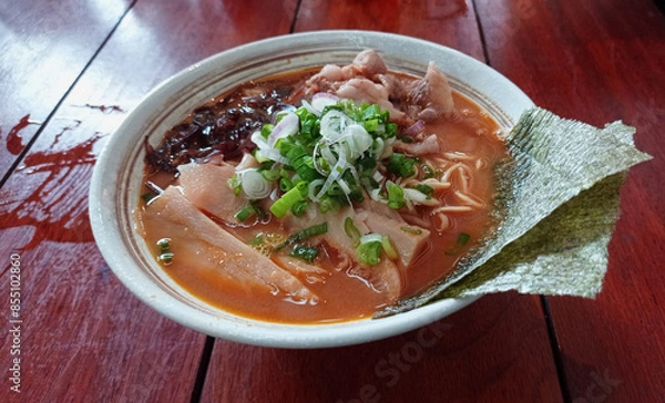 Fototapeta Spicy curry noodles ramen with beef slices in the traditional Japanese ramen restaurant on a wooden table. Top view