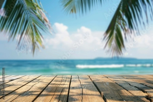 Fototapeta Top of wood table with seascape and palm leaves, blur bokeh light of calm sea and sky at tropical beach background. Empty ready for your product display montage. summer vacation background concept