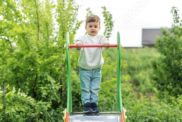 Fototapeta Happy toddler playing on colorful slide. Playground.