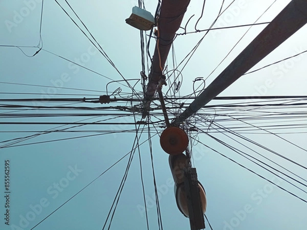 Fototapeta A power pole with many wires and cables hanging